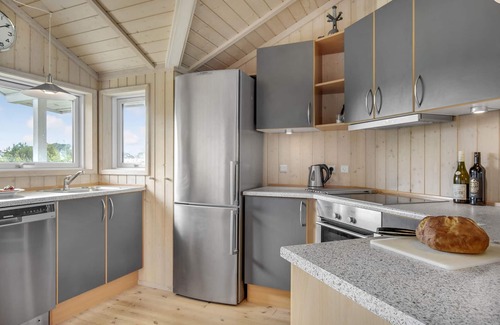 Havnsø House | The cottage has an inviting kitchen-living room with a fireplace and a partially covered terrace.
