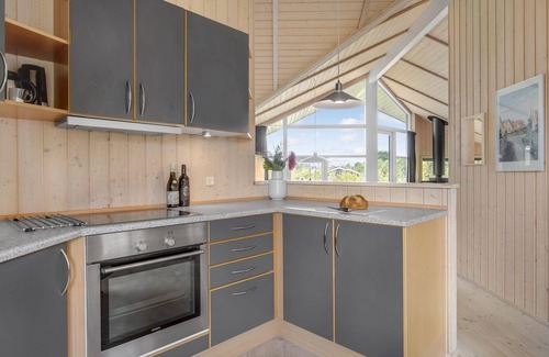 Havnsø House | The cottage has an inviting kitchen-living room with a fireplace and a partially covered terrace.