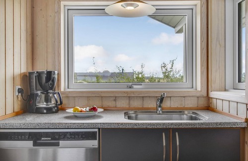 Havnsø House | The cottage has an inviting kitchen-living room with a fireplace and a partially covered terrace.