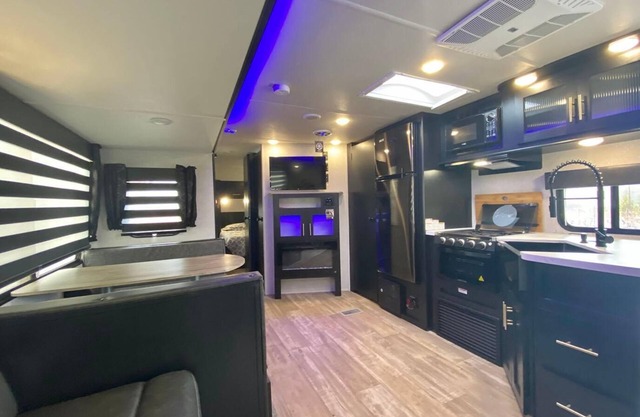 Cherokee RV features a queen-sized bed, dining area, and full kitchen.
