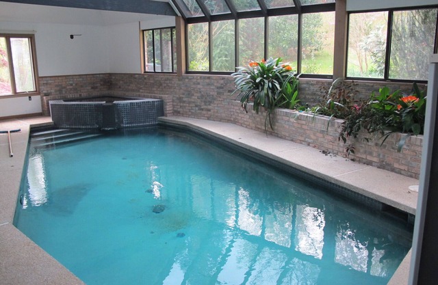 Indoor pool and spa in contemporary French home secluded in surrounding woods