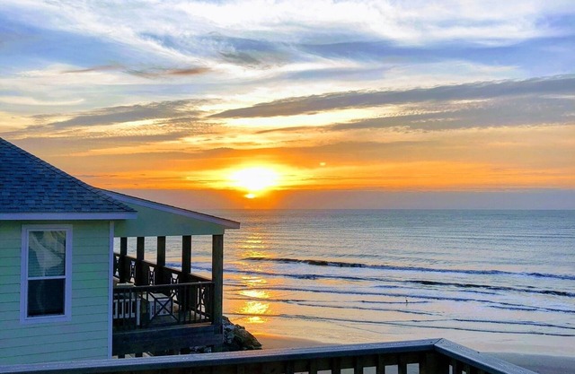Martinis & Bikinis, a beach front house with toes in the sand drink in the hand.