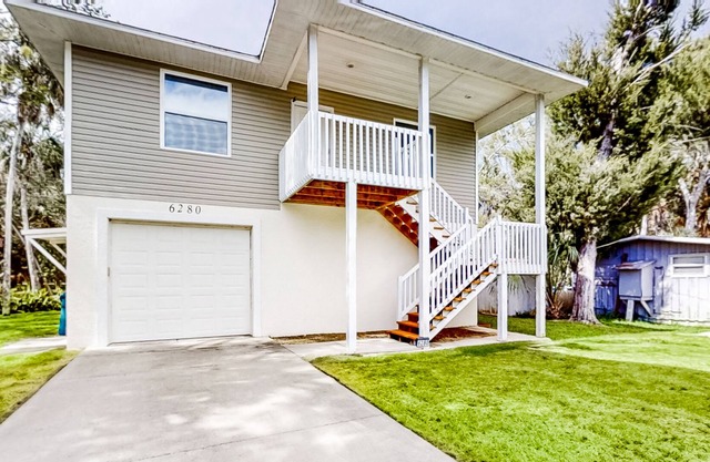 Palm-lined home with water access, game room, balcony, W/D, and central AC
