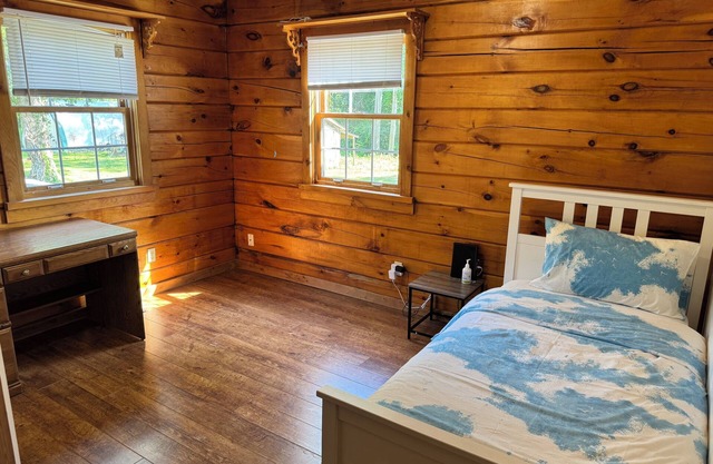 Serene log home on spacious land with trees and a small farm.