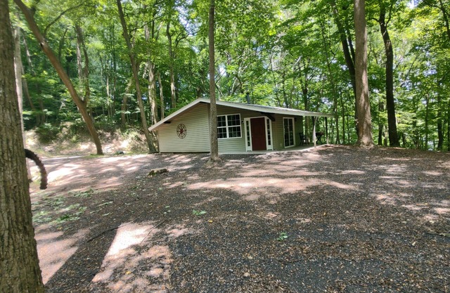 The Chalet is located in the woods of a gated property with a covered porch.