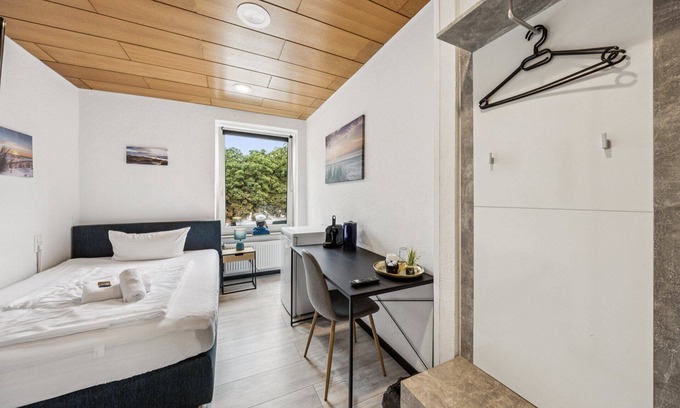 Wilhelmshaven Hotel | Cozy single room, flat-screen TV, and modern bathroom with shower. Ideal for singles and short stays – enjoy a relaxed atmosphere with warm wood accents and coastal charm.