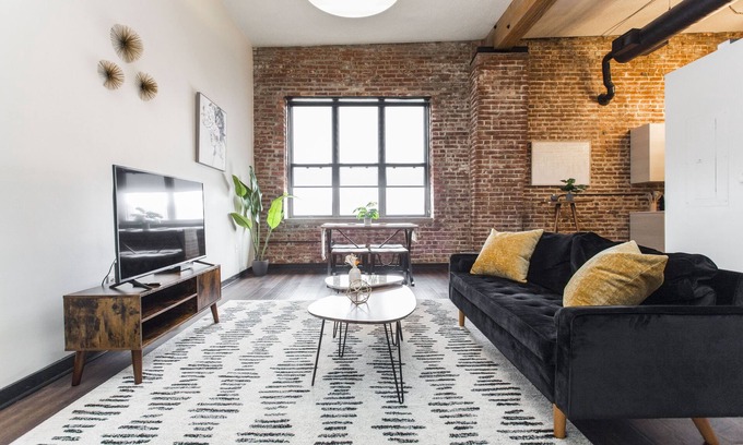 Kansas City Apartment | Exposed brick, wood beams, & chic touches give this loft serious style. Enjoy skyline views from the rooftop, a full kitchen with coffee bar, king bed, on-site gym, & quick access to the free KC streetcar. Walk to shops/dining, and the City Market!