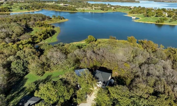 Little Elm House | Lakefront retreat just steps from Lake Lewisville! Enjoy 341 ft of shoreline, a private cove, sandy beach, fire pit, and pergola with built-in grill. Inside: lake views, travertine floors, cozy fireplace, and an upstairs game room with balcony.