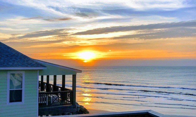 San Luis House | Martinis & Bikinis, a beach front house with toes in the sand drink in the hand.